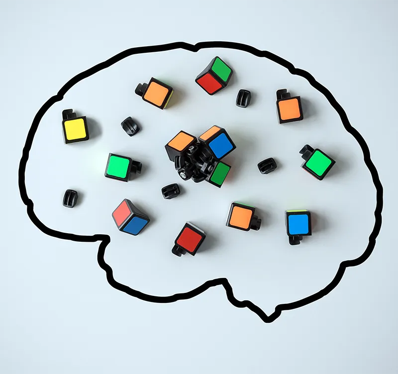 psychology_quiensoy2 Ilustración de un cerebro con piezas de un cubo de Rubik desordenadas en su interior, representando los desafíos y complejidades del pensamiento y la mente humana.